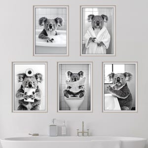 May include: Set of five black and white framed prints featuring a koala in different bathroom scenarios. The koala is taking a bath, brushing its teeth, reading a newspaper, holding a roll of toilet paper, and wearing a bathrobe.