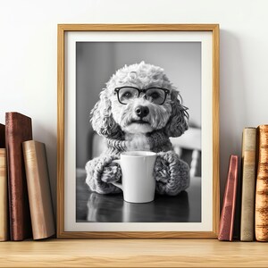 May include: A black and white photo of a dog wearing glasses and a sweater, holding a white mug. The dog is sitting at a table with a book in the background.