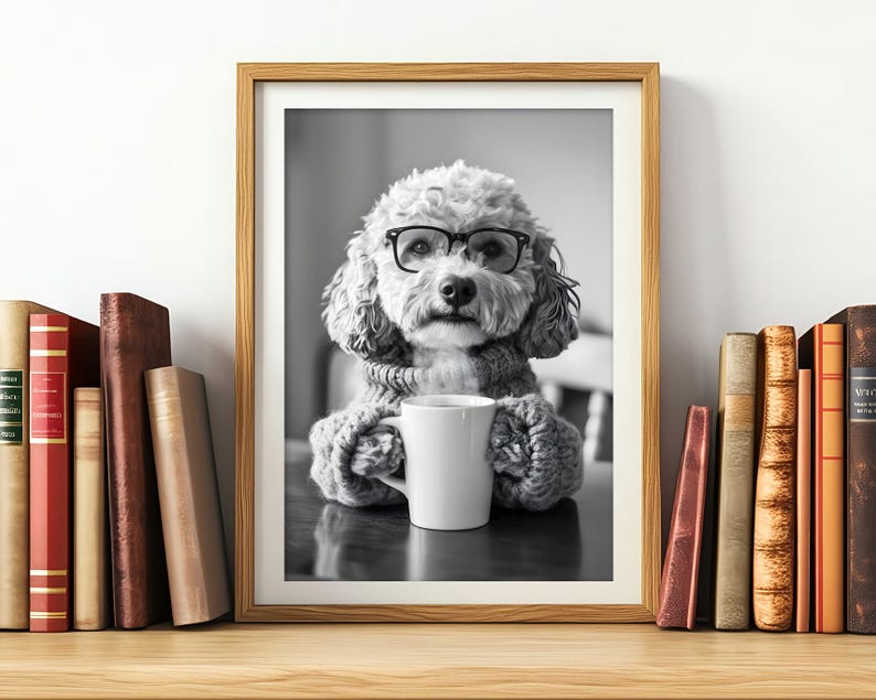 May include: A black and white photo of a dog wearing glasses and a sweater, holding a white mug. The dog is sitting at a table with a book in the background.