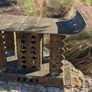May include: A small, intricately carved wooden stool with a curved top and a decorative design. The stool is made of dark wood and has a rustic, antique look.
