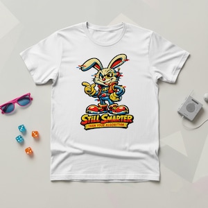 Op de afbeelding: Wit T-shirt met een cartoon konijn met een zonnebril en een blauw en rood pak. De tekst "Still Smarter Than Your Algorithm" staat eronder. Het ontwerp heeft een glitch-effect.