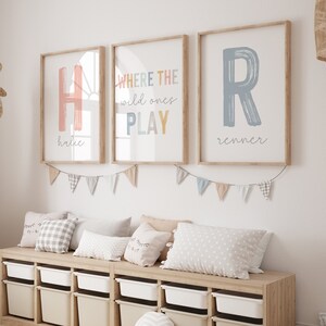 May include: A light wood storage bench with six white and beige storage bins. The bench is decorated with a string of pastel colored flags and three framed prints. The prints feature the letters H and R in pink and blue, and the text "WHERE THE wild ones PLAY".