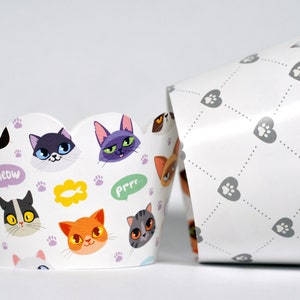 May include: White cupcake liners with a scalloped edge. The liners feature a pattern of cats with different expressions, paw prints, and the words "Meow" and "Prrr".