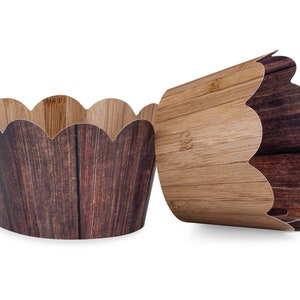 May include: Two brown and beige paper cupcake liners with a woodgrain pattern. The liners have a scalloped edge.