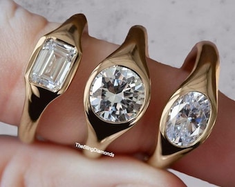 Puede incluir: Tres anillos de oro con diferentes tallas de diamantes: esmeralda, redonda y ovalada. Los anillos están engastados en un estilo biselado, con los diamantes en un lugar destacado. Los anillos están sobre un fondo claro.