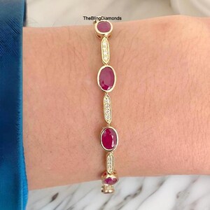 Puede incluir: Pulsera dorada con rubíes ovalados y pequeños diamantes. El diseño de la pulsera alterna secciones de rubíes y diamantes. El texto "TheBlingDiamonds" es visible.