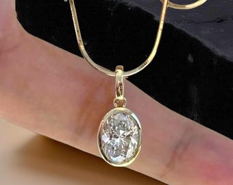 May include: A gold necklace with an oval diamond pendant. The diamond is set in a gold bezel. The necklace is shown against a dark backdrop. The text "TheBlingDiamonds" is visible in the upper left corner of the image.