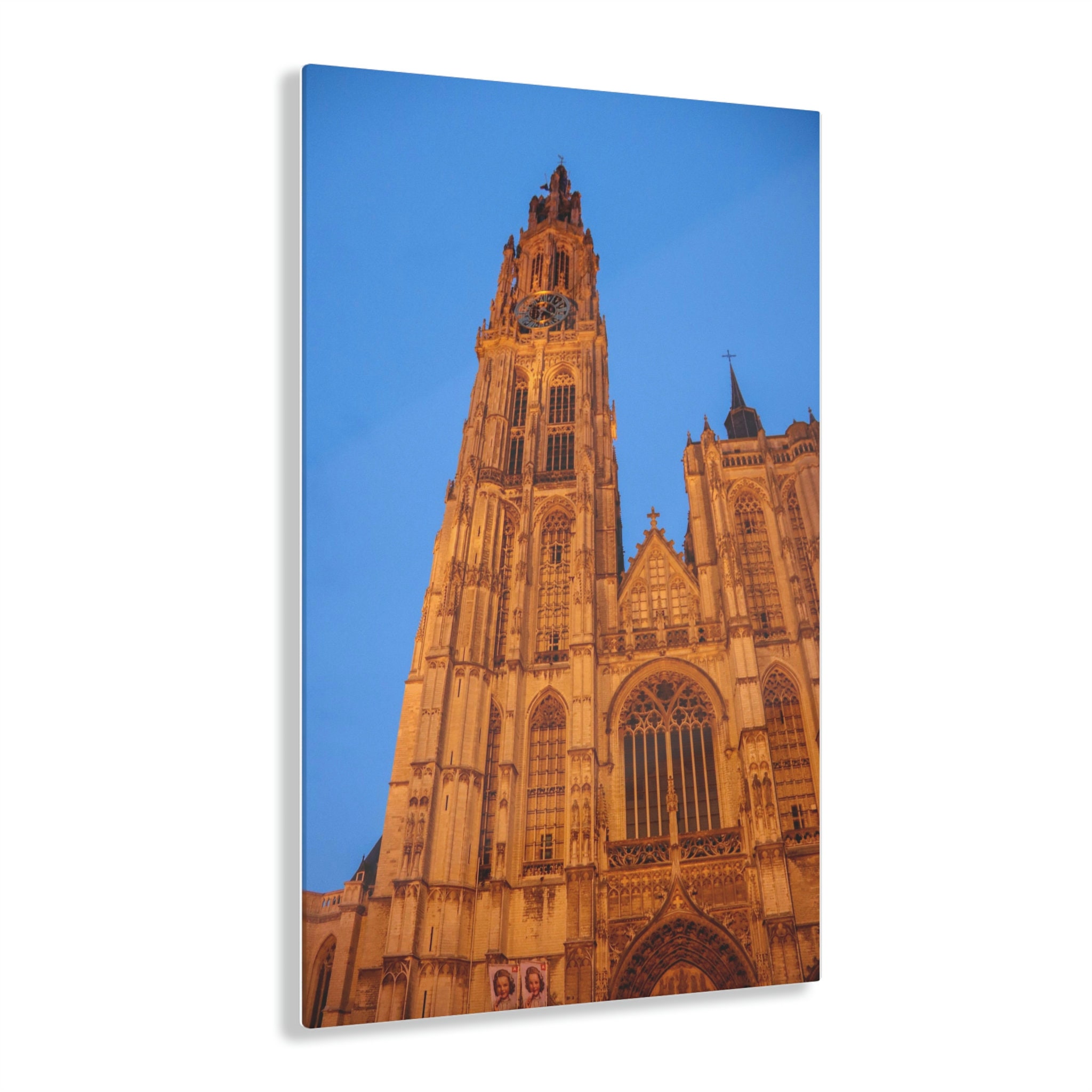 The majestic spire of the Cathedral of Our Lady in Antwerp, soaring above surrounding buildings into a clear sky, showcasing intricate Gothic architecture.
