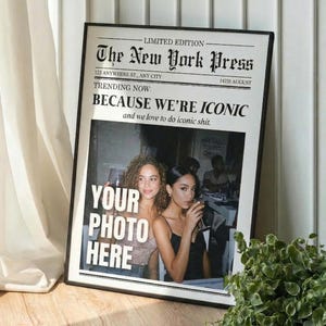 Könnte beinhalten: Ein gerahmter Druck, der wie eine Zeitungsseite gestaltet ist. Die Schlagzeile lautet "The New York Press" mit dem Text "BECAUSE WE'RE ICONIC" und "YOUR PHOTO HERE". Das Bild zeigt zwei Frauen, die Getränke halten.