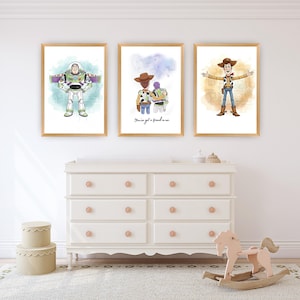 May include: Three framed wall art prints featuring watercolour-style illustrations of characters. The left print shows a space ranger, the centre print shows two characters with the text "You've got a friend in me," and the right print shows a cowboy.