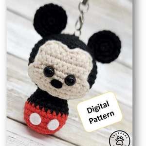 May include: Crocheted Mickey Mouse keychain with red shorts and white buttons. The keychain is attached to a red string. The image includes the text "Mickey Mouse" and "Digital Pattern".