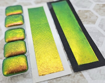 May include: Four small square samples of iridescent green and gold paint with a larger sample of the same paint on a white background. The word "Oleander" is printed on the bottom of the sample card.