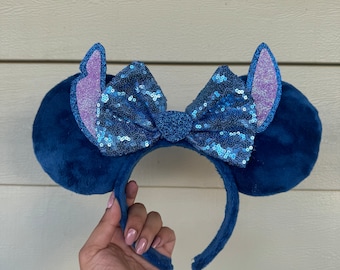 May include: Blue fuzzy Minnie Mouse ears with a blue and purple sequin bow.