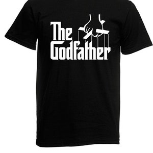 Könnte beinhalten: Schwarzes T-Shirt mit einer weißen Grafik einer Hand, die Fäden steuert, mit dem Text "The Godfather" darunter.
