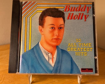 May include: A CD case with a blue and yellow design featuring a portrait of Buddy Holly. The text on the case reads "Buddy Holly 30 All Time Greatest Hits The Entertainers".