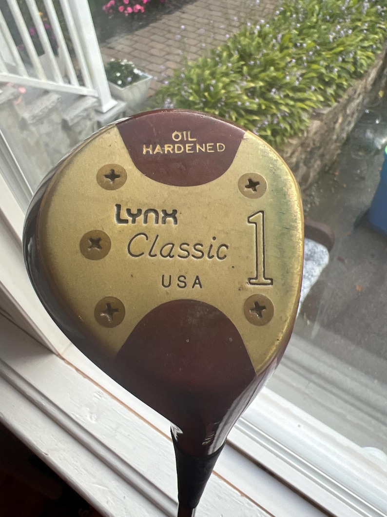 以下が含まれることがあります： 「Lynx Classic 1」と「Oil Hardened」の文字が書かれた、金色と茶色のゴルフクラブヘッド。クラブヘッドはアメリカ製です。