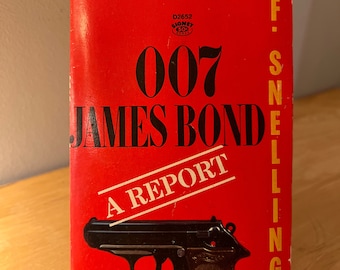 Könnte beinhalten: Ein rotes Taschenbuch mit dem Titel "007 James Bond A Report" und einer schwarzen und braunen Pistole auf dem Cover. Das Buch ist ein Signet-Buch, vollständig und ungekürzt.
