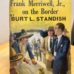 May include: A vintage book cover featuring an illustration of men in a Western setting. The book title is "Frank Merriwell, Jr., on the Border" by Burt L. Standish. The book is part of "The Merriwell Series" and is number 231.