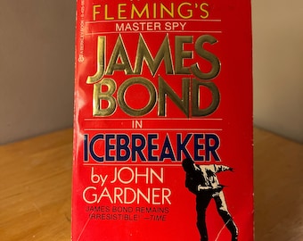 Könnte beinhalten: Ein rotes Taschenbuch mit einem goldenen Titel, "James Bond in Icebreaker von John Gardner". Das Cover zeigt eine schwarze Silhouette eines Mannes im Anzug, der mit einer Waffe in der Hand rennt.