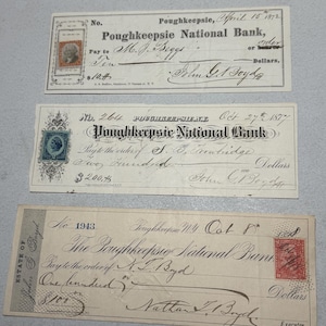 Puede incluir: Tres cheques antiguos del Poughkeepsie National Bank, fechados entre 1872 y 1888. Los cheques presentan una escritura ornamentada y sellos. Los cheques están en varios estados de conservación.