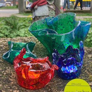 Könnte beinhalten: Drei Glasschalen in verschiedenen Farben und Formen. Die Schalen sind aus recyceltem Glas und haben eine gesprenkelte Oberfläche. Die Schalen sind auf einer Steinoberfläche angeordnet. Der Text "EINFACH wunder.bar MACHEN" ist in der unteren rechten Ecke des Bildes sichtbar.