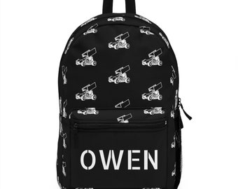 May include: Black backpack with a white print of a race car repeated all over the bag. The name "OWEN" is printed in white on the front pocket.