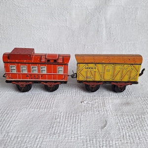 May include: A red and yellow toy train set with a passenger car labeled "A.T. & S.F. X 104" and a freight car labeled "Santa Fe Freight Car".