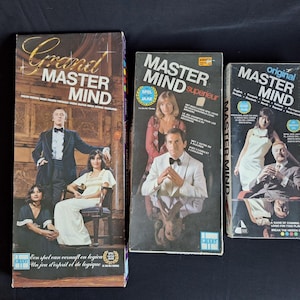 May include: Three vintage Master Mind board game boxes. The boxes feature images of people in formal attire. The largest box is labeled "Grand Master Mind" and includes text in multiple languages. The other two boxes are labeled "Master Mind" and "original Master Mind".
