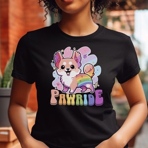 Puede incluir: Camiseta negra con un chihuahua de dibujos animados con una cola arco&iacute;ris y el texto "PAWRIDE" en letras arco&iacute;ris.