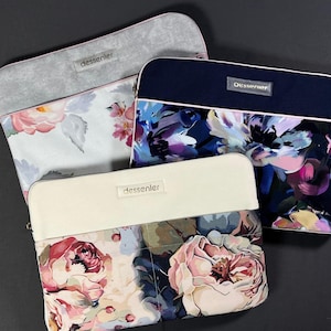 May include: Three floral print laptop sleeves with the brand name "dessenler" on each. The sleeves feature a variety of floral patterns in shades of pink, blue, and purple, with neutral-colored tops and zippers.