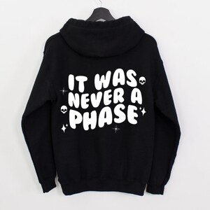 K&ouml;nnte beinhalten: Schwarzer Kapuzenpullover mit wei&szlig;em Text, der "It was never a phase" lautet, mit Totenkopf- und Stern-Akzenten.