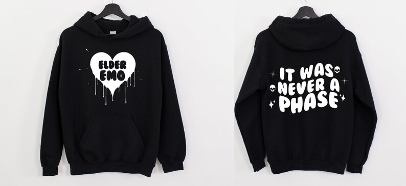 K&ouml;nnte beinhalten: Schwarzer Kapuzenpullover mit einem wei&szlig;en Herzdesign, auf dem "Elder Emo" steht und Farbe tropft. Die R&uuml;ckseite des Pullovers hat einen wei&szlig;en Text, der "It was never a phase" mit Sternen und Alien-Gesichtern sagt.