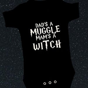 May include: Black baby bodysuit with white text reading "DAD'S A MUGGLE MAM'S A WITCH". The bodysuit has three press studs at the bottom and a round neck. The background is a dark, starry night.