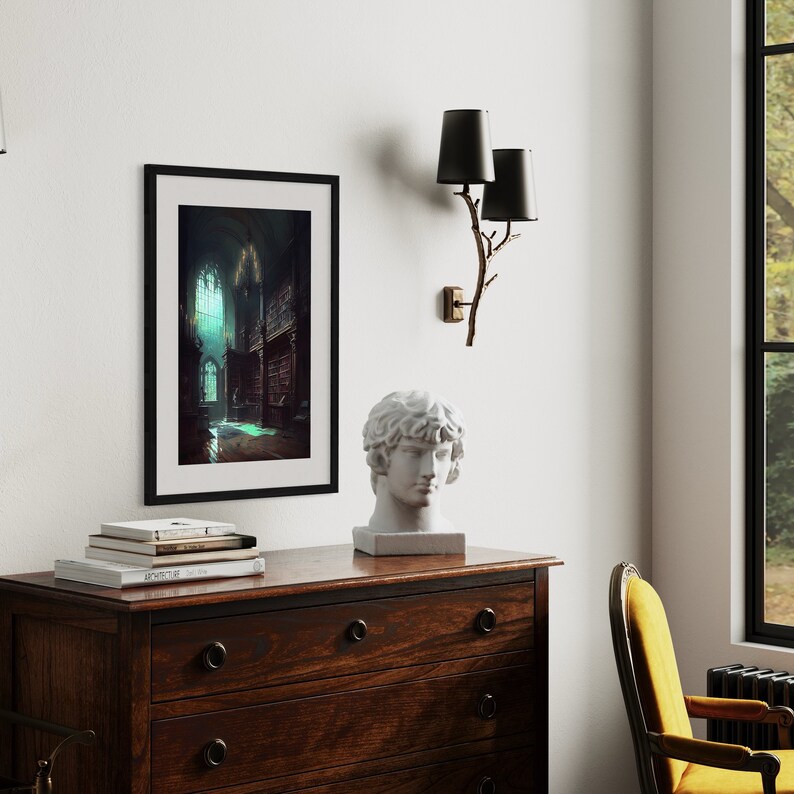 May include: A black framed print of a dark, gothic interior with a large stained glass window. The print is hanging on a white wall above a wooden dresser with a white plaster bust of a man on top. A black and gold wall sconce with two black lampshades is on the wall to the right of the print.