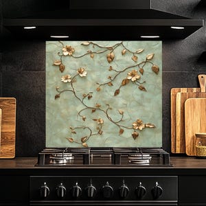 Può includere: Un paraschizzi da cucina decorativo con un design floreale. Il paraschizzi presenta uno sfondo blu chiaro con viti e fiori dorati.