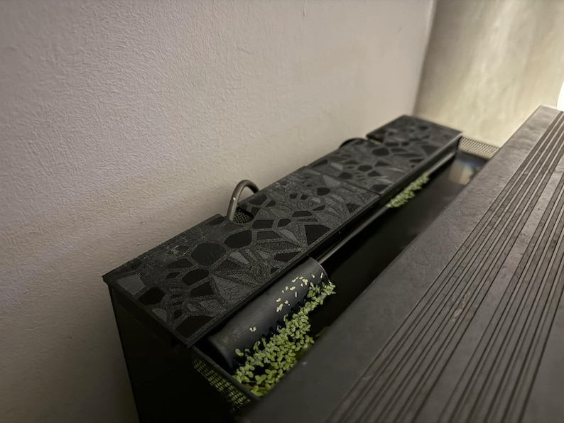Puede incluir: Un acuario rectangular negro con tapa estampada y asa met&aacute;lica. El acuario contiene plantas acu&aacute;ticas y un filtro cil&iacute;ndrico negro. El dise&ntilde;o presenta formas geom&eacute;tricas y una est&eacute;tica elegante y moderna.