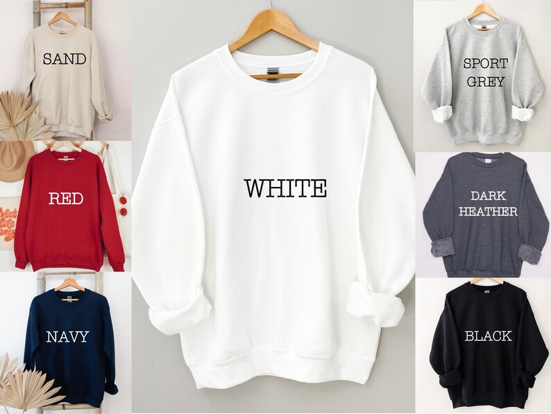 May include: A white sweatshirt with the word "WHITE" printed on the front. The sweatshirt is available in 10 colors: sand, red, navy, black, sport grey, dark heather, white, light heather, pink, and teal.