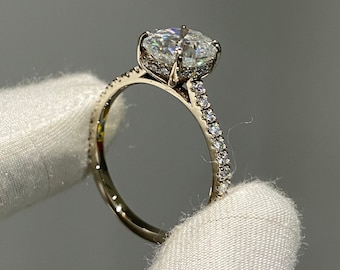 May include: A gold engagement ring with a large, round, clear center stone and a band of smaller, clear stones.