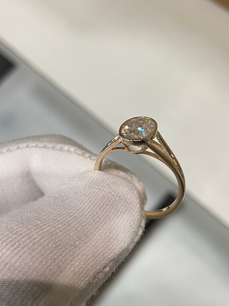 Op de afbeelding: Een gouden ring met een bezel-setting met een ronde, heldere edelsteen.