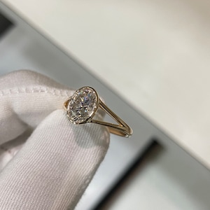 Op de afbeelding: Een gouden ring met een grote ovale, heldere edelsteen.