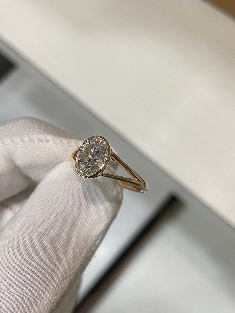 Op de afbeelding: Een gouden ring met een grote ovale, heldere edelsteen.