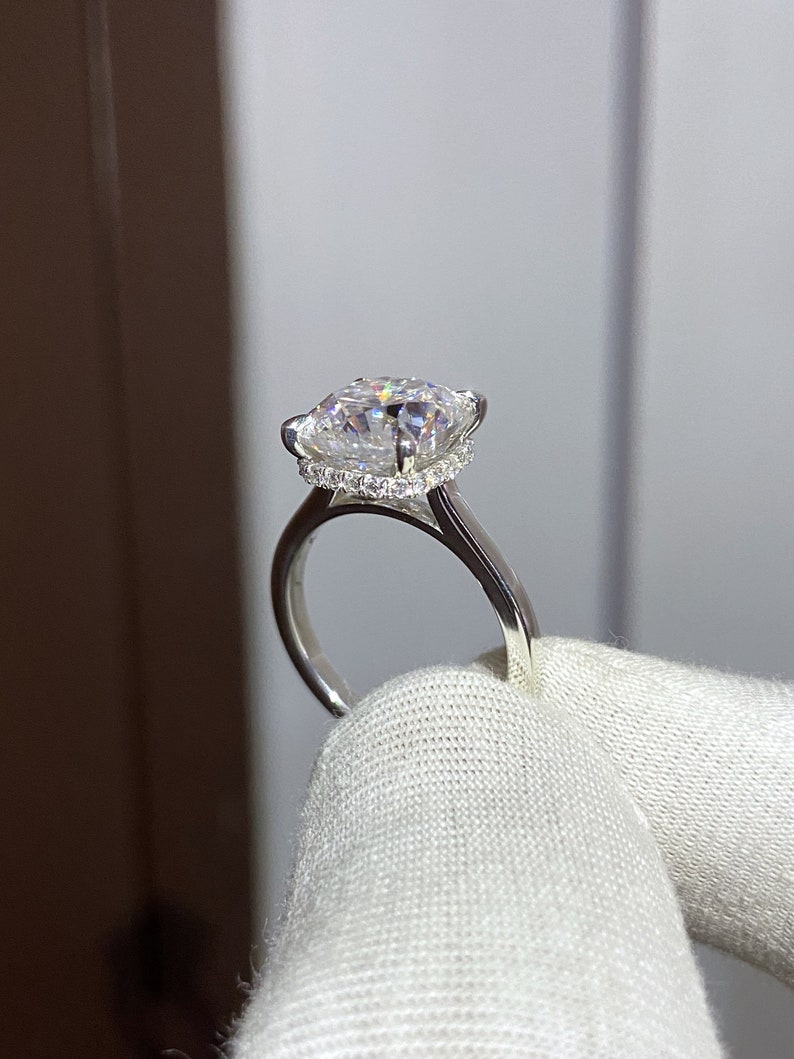 May include: A silver ring with a large, clear, square-shaped diamond set in a halo of smaller diamonds.