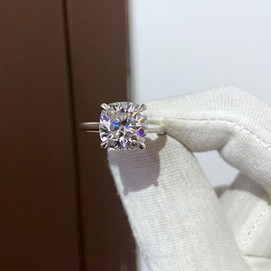 May include: A silver ring with a large, clear, cushion-cut diamond.