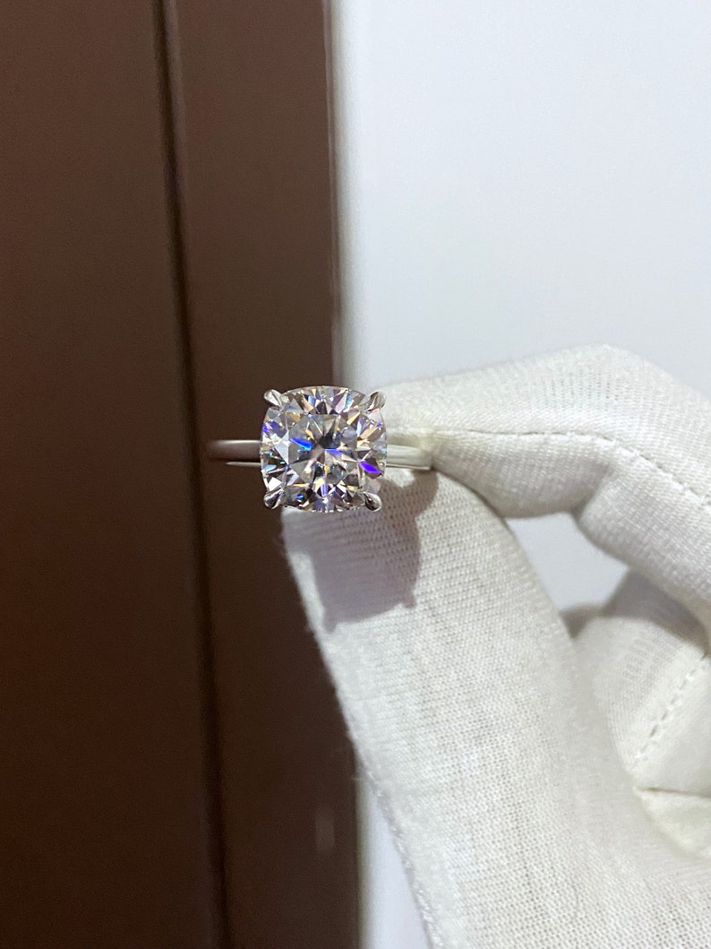 May include: A silver ring with a large, clear, cushion-cut diamond.