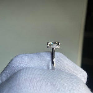 May include: A silver ring with a large, clear, round diamond set in a halo of smaller diamonds.