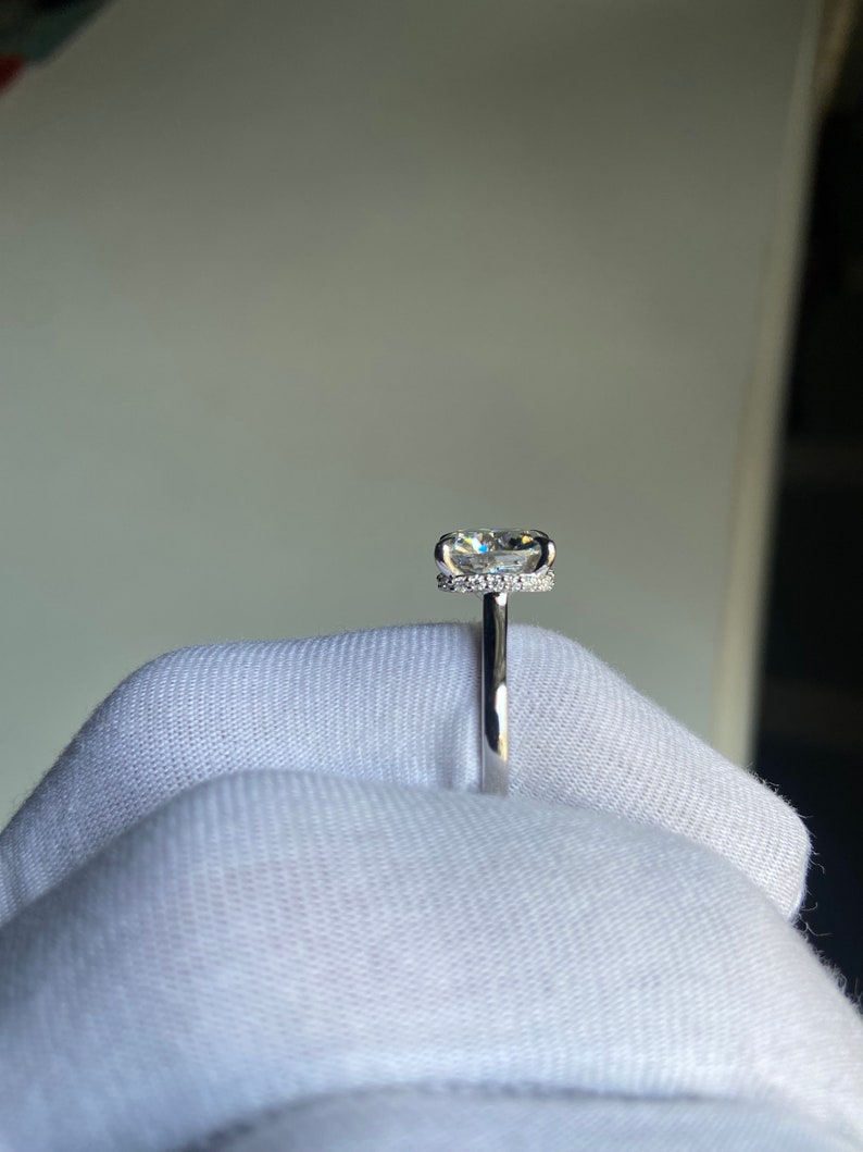 May include: A silver ring with a large, clear, round diamond set in a halo of smaller diamonds.