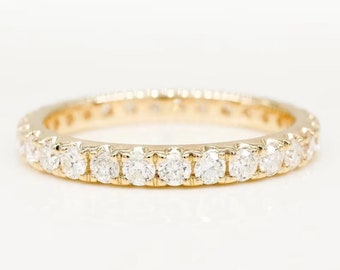 May include: A gold band with a row of small, round diamonds set in a continuous line.