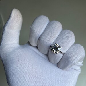 May include: A white gold ring with a large, clear, square-shaped diamond.