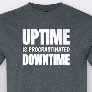 May include: A dark heather gray short-sleeved t-shirt featuring the white text UPTIME IS PROCRASTINATED DOWNTIME printed in a bold, sans-serif font across the chest. The garment has a classic crew neckline and a standard fit construction.