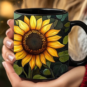 May include: Black coffee mug with a sunflower design. The sunflower is yellow with a dark brown center and green leaves.